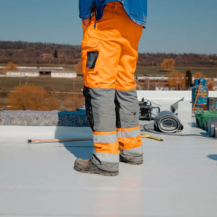 worker standing on a flat roof with pvc membrane insulation system